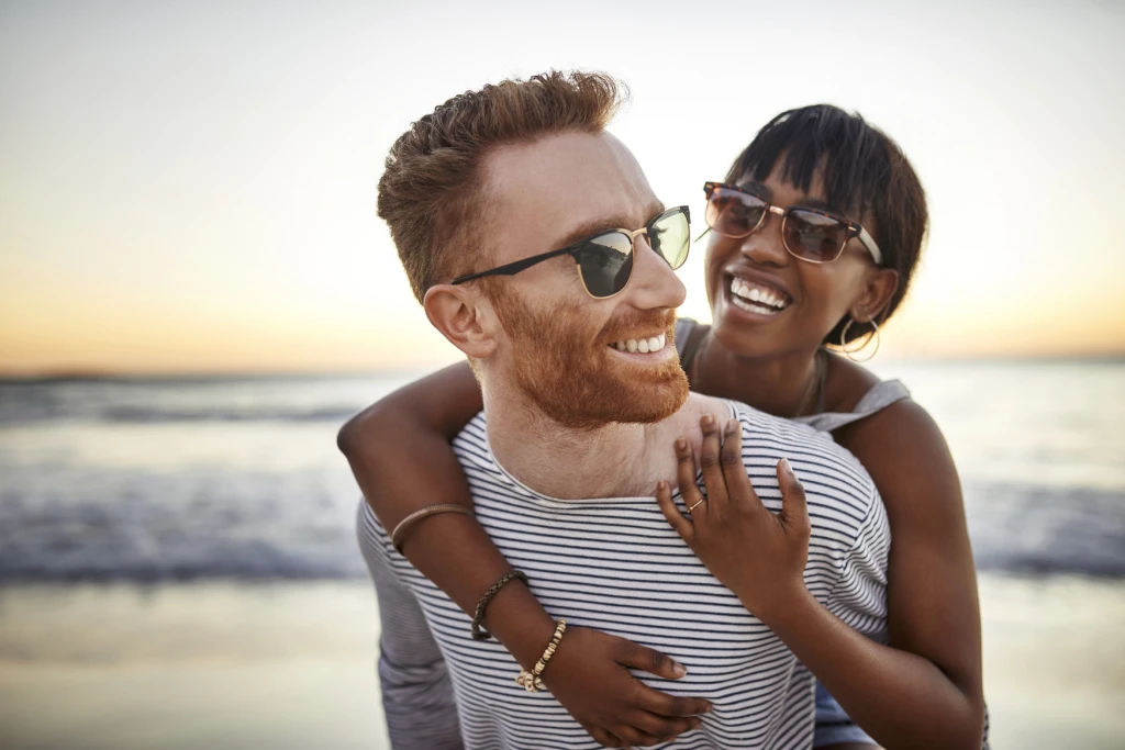 two people hugging on a beach at sunset