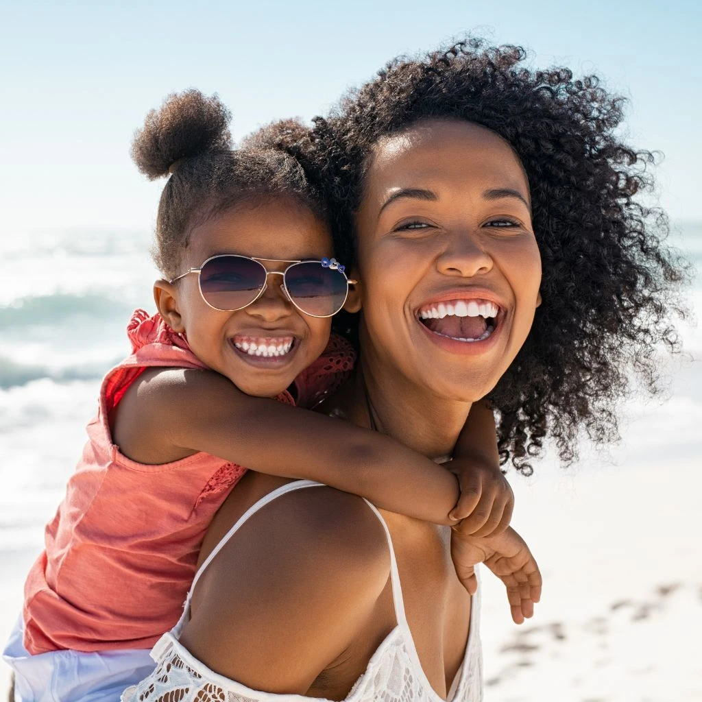 smiling woman with a small child on her back